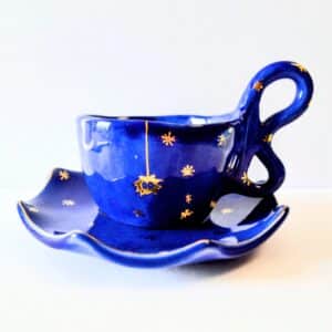 Handmade dark blue ceramic mug with a base, yellow spider motif and stars.