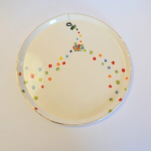 Dish with gold rim, painted spider watering tiny colorful flowers.