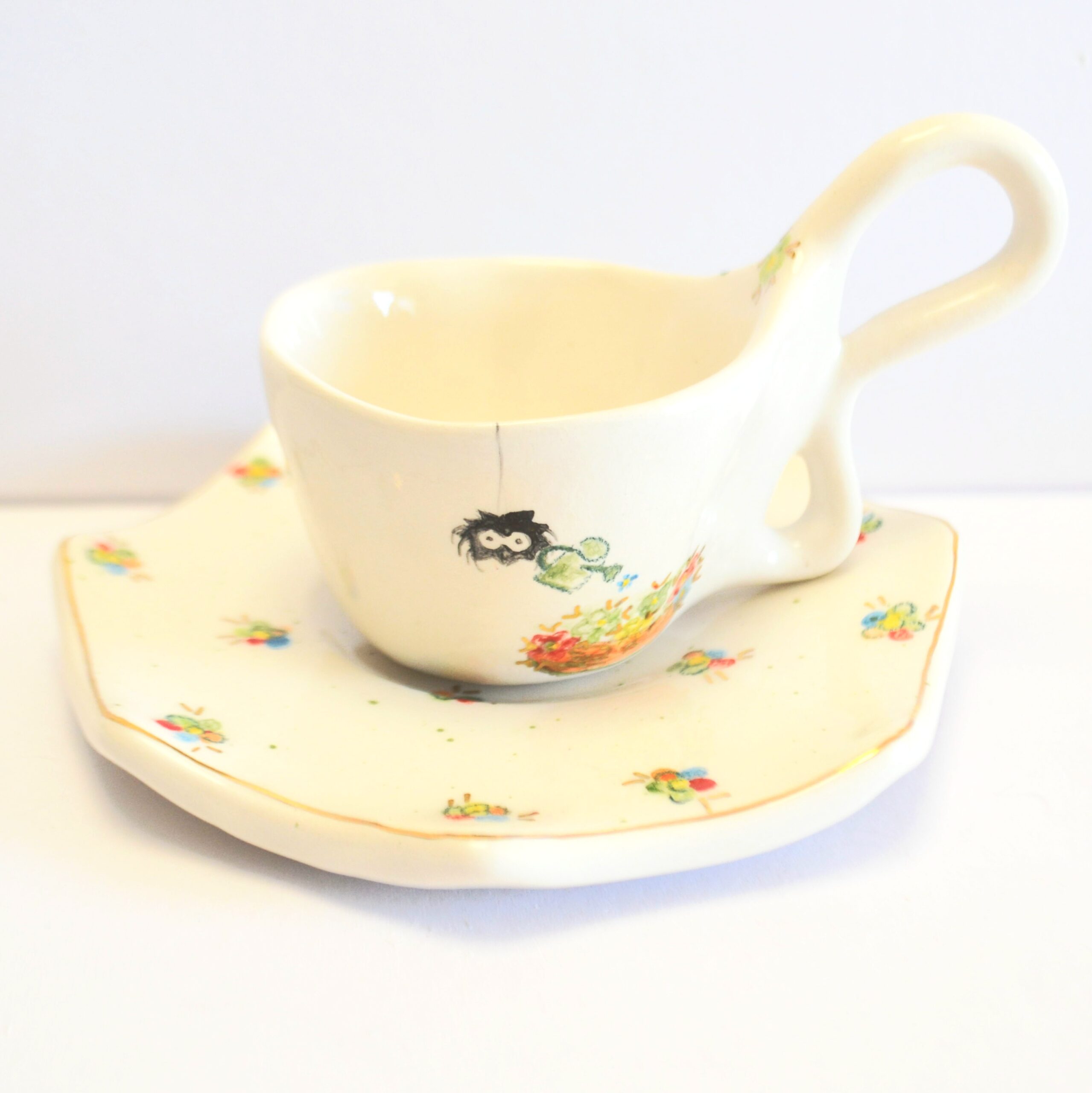 Front of mug and soucer. Hand-painted spider watering tiny colorful flowers.