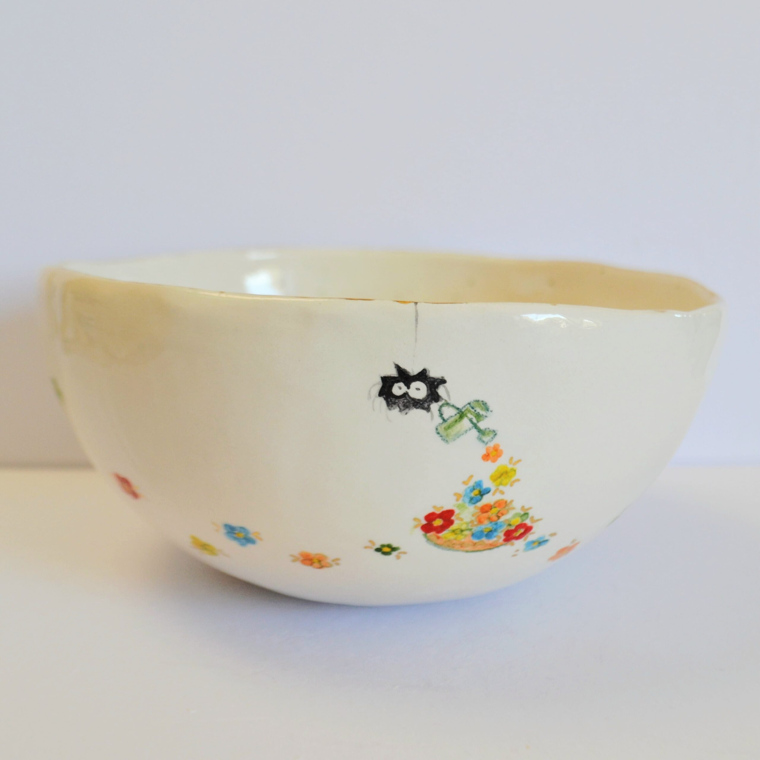 Front view of a white ceramic bowl featuring a whimsical hand-painted spider watering a trail of tiny colorful flowers.